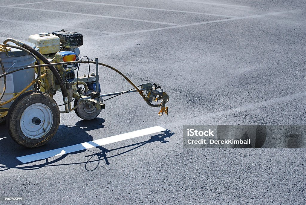 Striping machine painting lines onto fresh asphalt.
